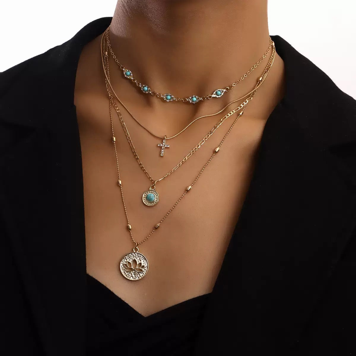 Model wearing layered warm-toned necklaces with blue stone-style pendant details