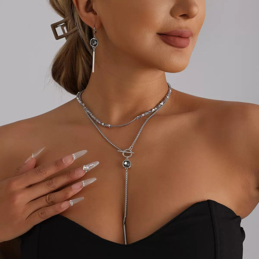 Model wearing layered silver-tone necklace styling for an evening occasion